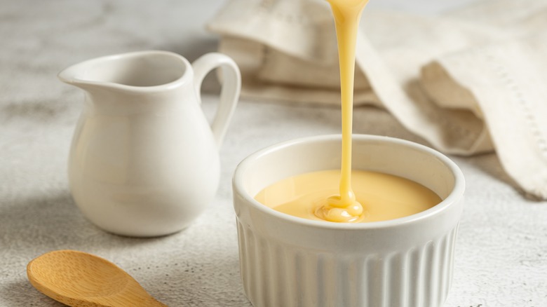 Sweetened condensed milk pouring into ramekin