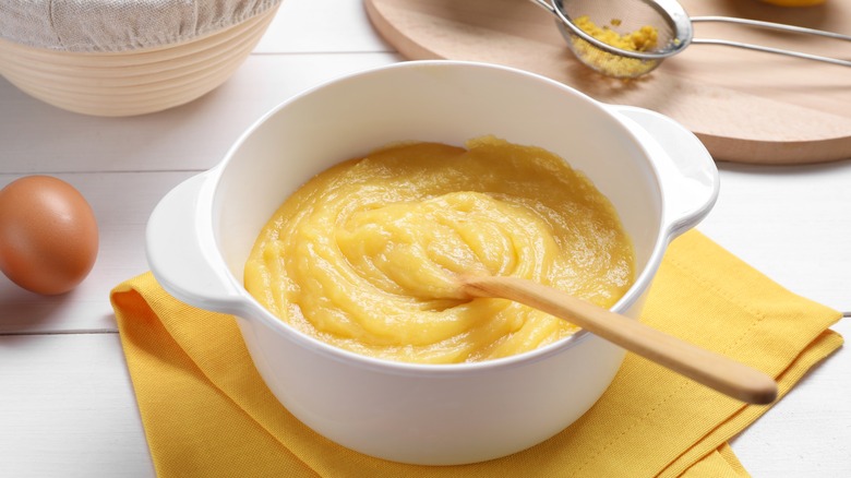 white bowl of lemon curd with wooden spoon