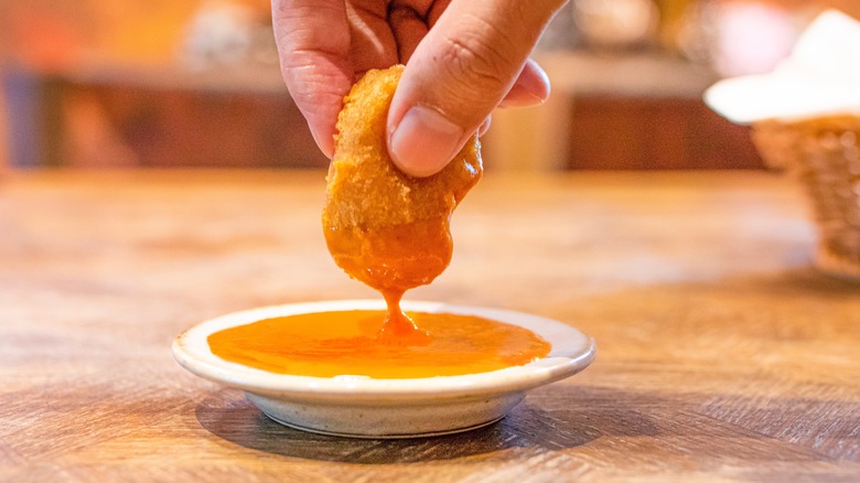 Person dipping chicken nugget in sauce