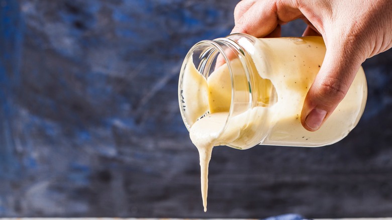 Hand pouring Caesar dressing