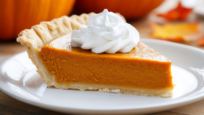 A slice of pumpkin pie topped with whipped cream