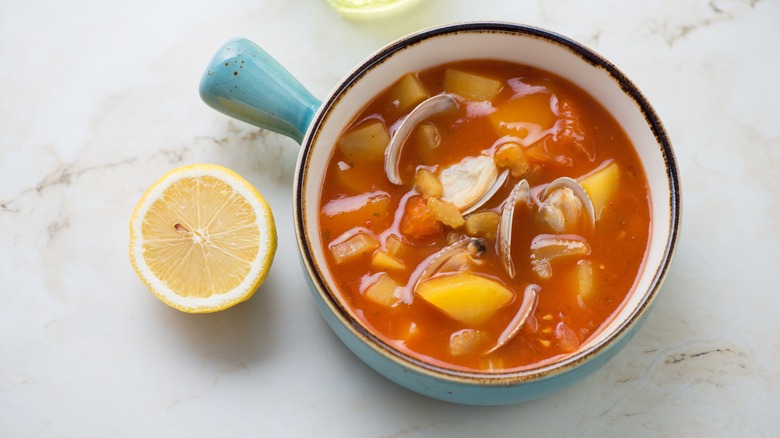 Manhattan clam chowder in blue bowl with lemon