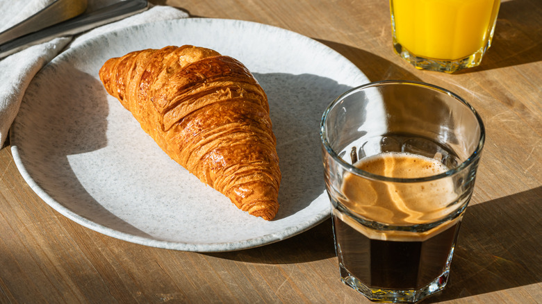 Croissant on a plate with a glass of espresso