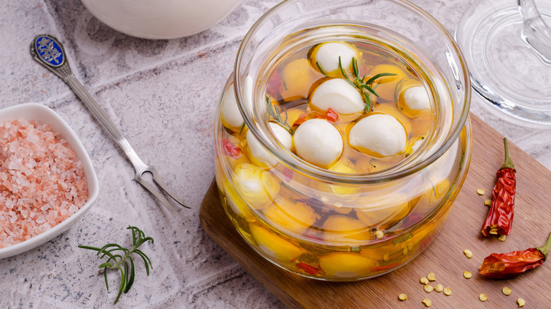 Mozzarella balls in a jar of olive oil with salt, peppers, and herbs