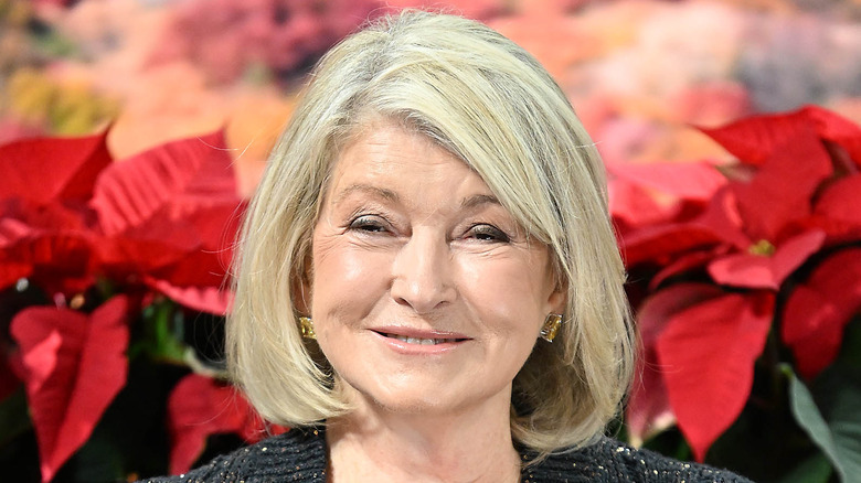 Martha Stewart smiling in front of poinsettias