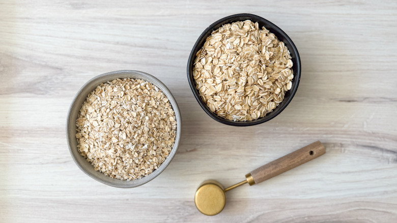 Quick oats and old-fashioned rolled oats in bowls with measuring spoon