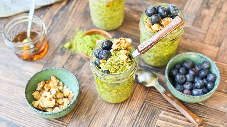 Matcha almond overnight oats in jars with fresh blueberries and maple almonds