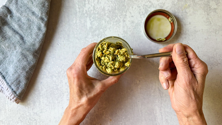 Stirring matcha almond overnight oats in jar