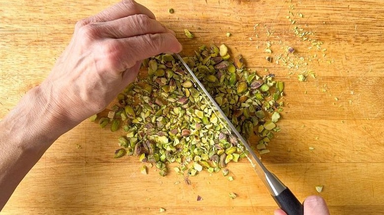 Chopping pistachios on cutting board with chef's knife