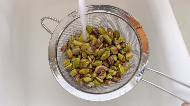 Rinsing pistachios under water in mesh strainer