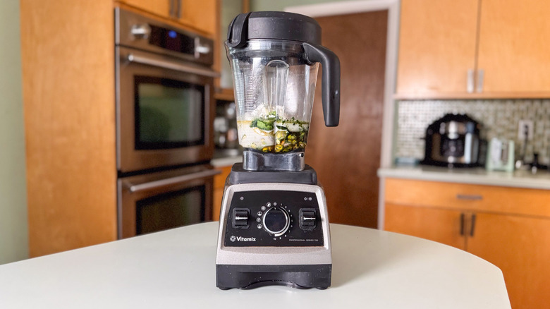 Pistachios, coconut cream, matcha powder, and honey in Vitamix blender on countertop