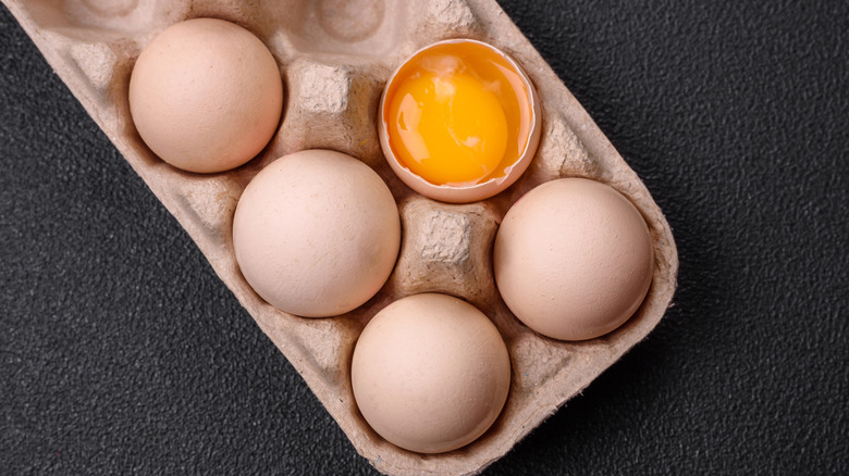 Egg yolk inside eggshell in carton