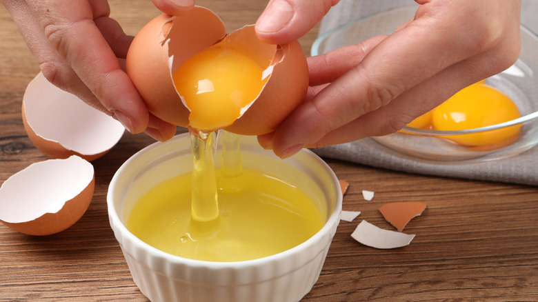 Hands separating eggs into bowls