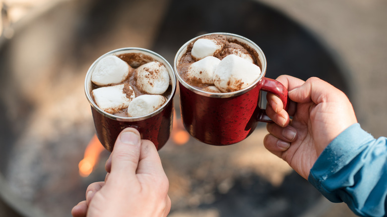 Two people holding mugs of hot chocolate with marshmallows