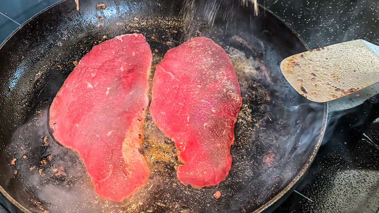 Minute steaks frying in a pan