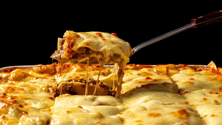 Slice of freshly cooked lasagna being taken out of a pan