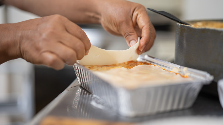 Person topping lasagna with fresh noodles