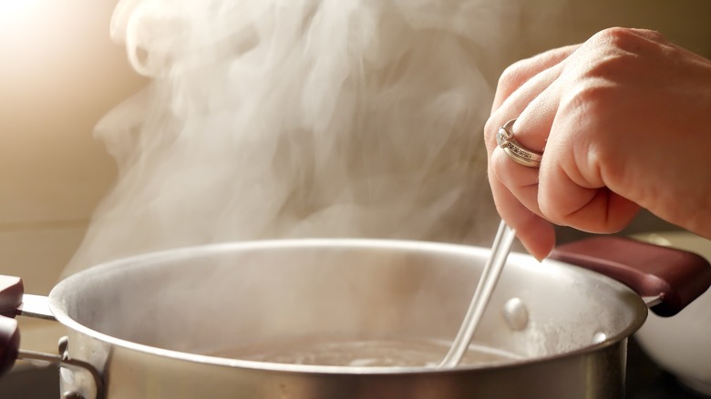 Person stirring steamy pot