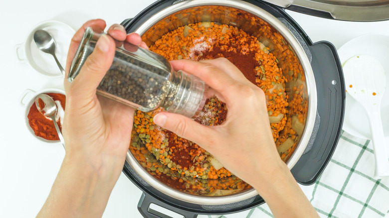 Person adding black pepper to soup in Instant Pot