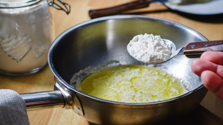 Person adding cornstarch to butter in pan