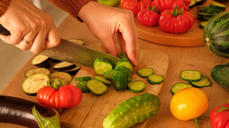 Person slicing Mediterranean vegetables