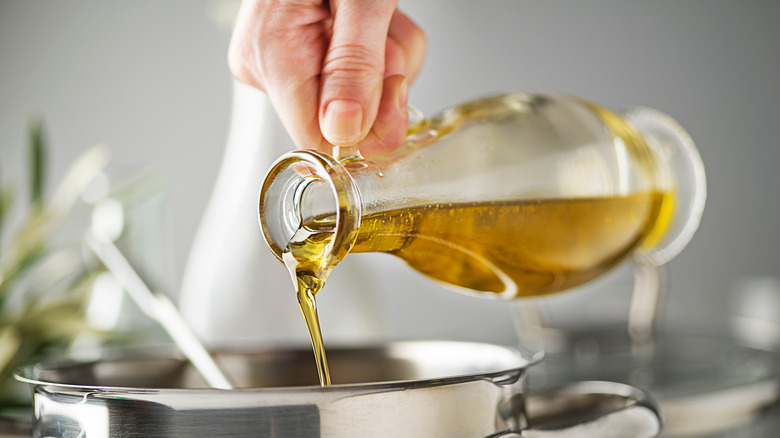 Person pouring oil into pot