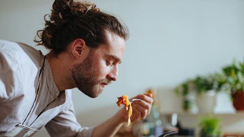 man tasting pasta on fork