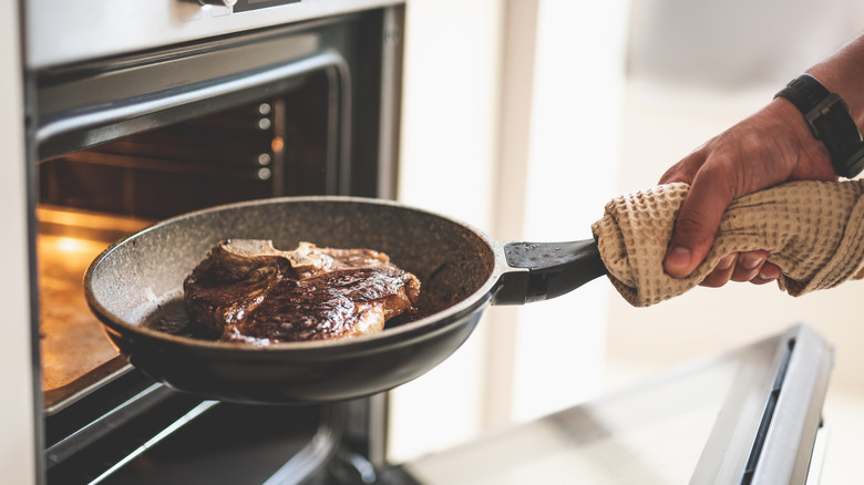 Cook placing steak in oven