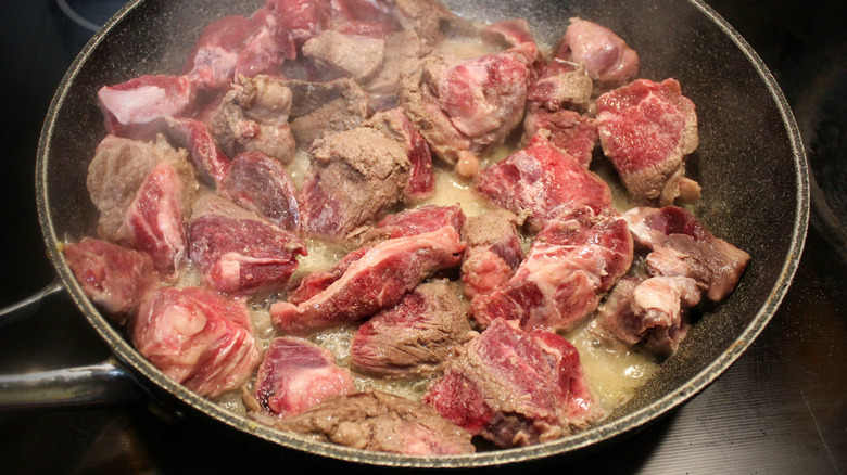 A pan with beef stew meat browning in oil