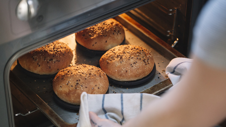 Home baker pulling baked  bread from oven