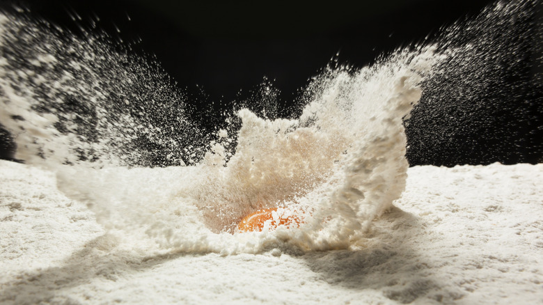 Flour on a counter with an egg