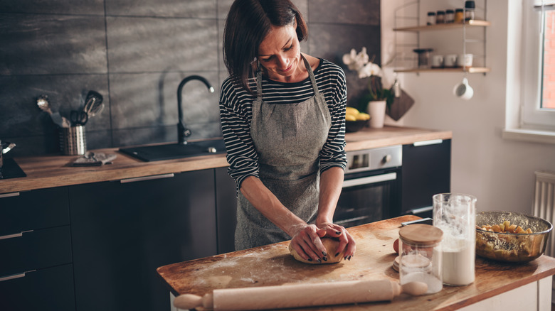 Woman in kitchen making loaf of bread