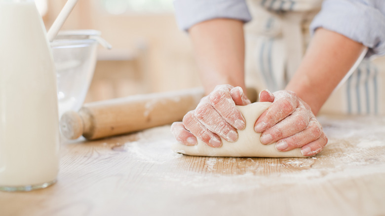 Women's hands kneading bread on counter