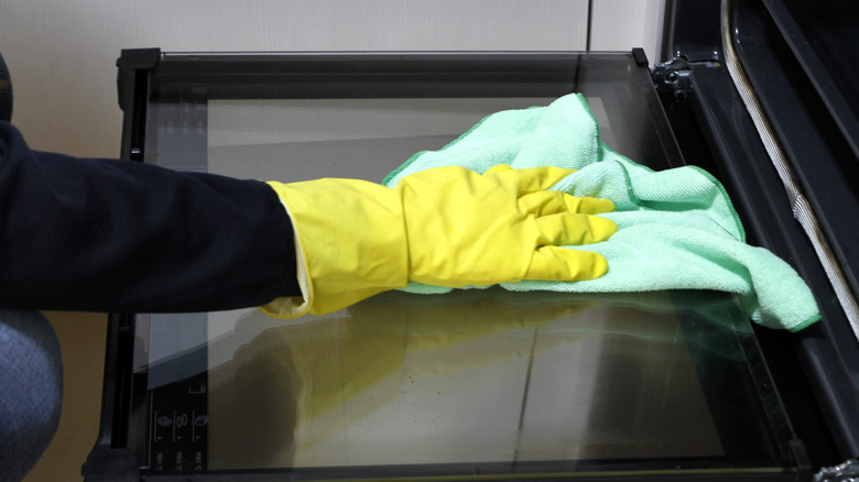 Person cleaning oven with cloth