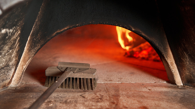 Cleaning pizza oven with a brush