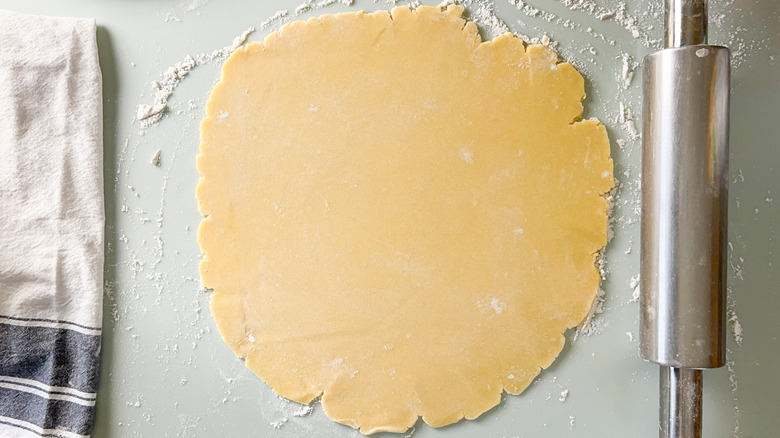 Rolled out quiche dough on floured counter top with rolling pin