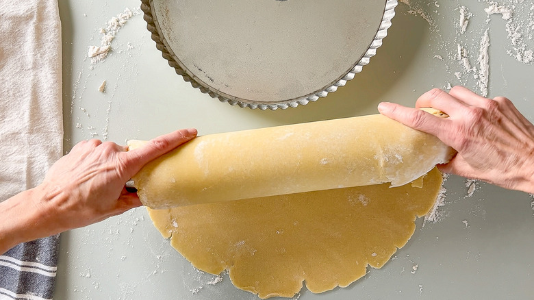 Transferring quiche dough on rolling pin to tart pan
