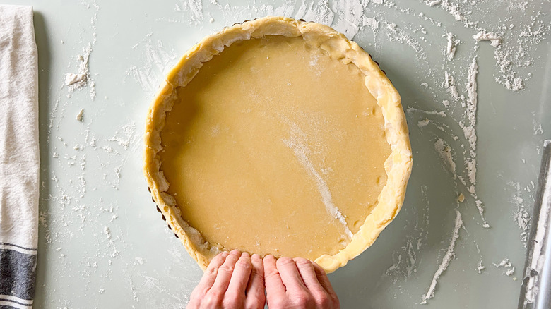 Pressing quiche dough into tart pan with fingers
