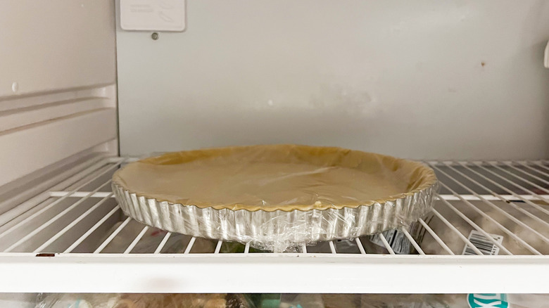 Unbaked quiche shell in tart pan in freezer