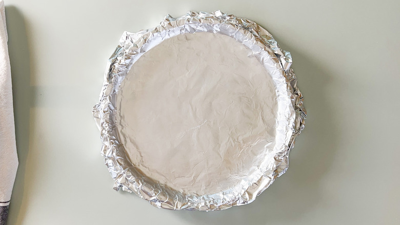 Quiche shell in tart pan covered with foil
