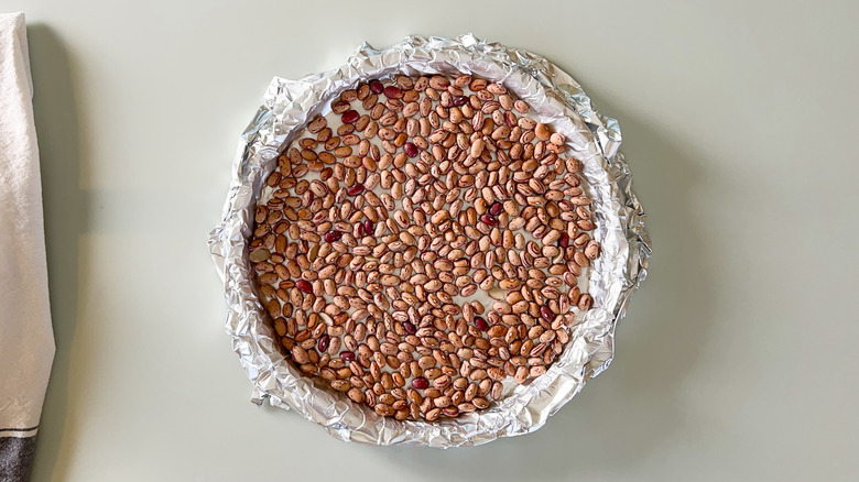 Dried beans on foil covered quiche shell in tart pan
