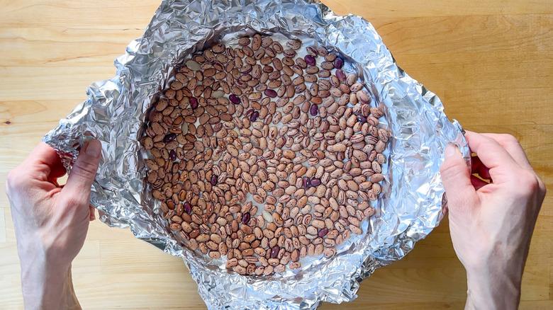 Dried beans and foil on quiche shell in tart pan
