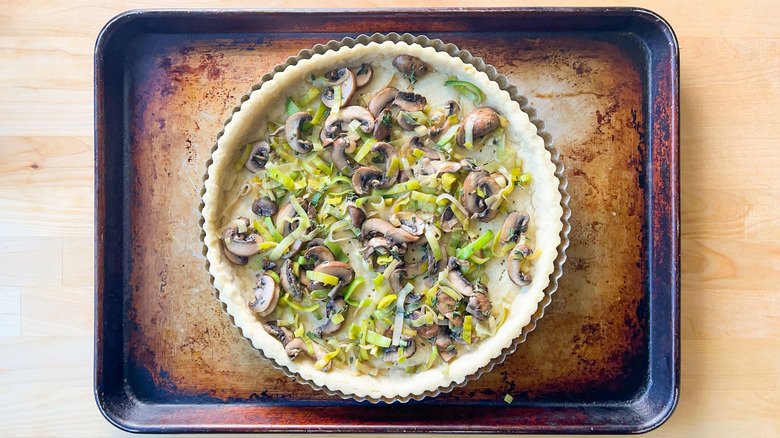 Leeks and mushrooms in baked quiche shell on baking sheet