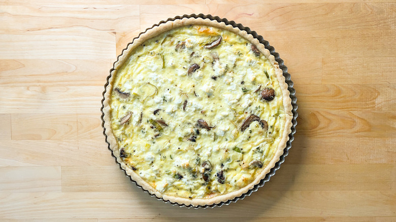 Mushroom and leek quiche in tart pan on counter top