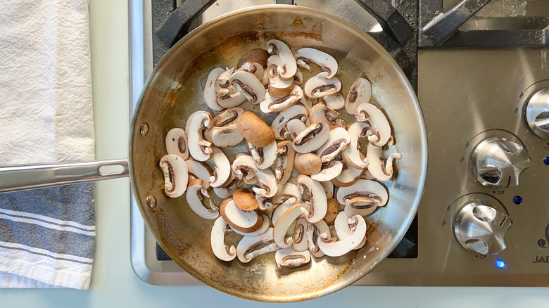Sliced mushrooms in saute pan on stove