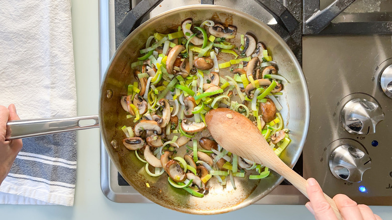 Sliced mushrooms and leeks in saute pan on stove