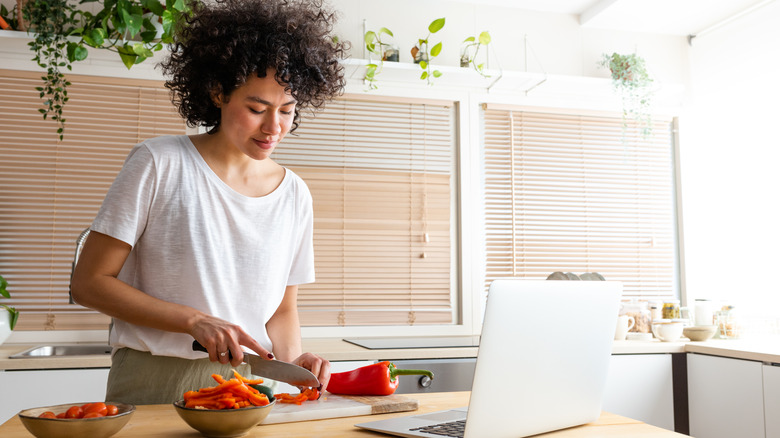 Woman prepping food by laptop