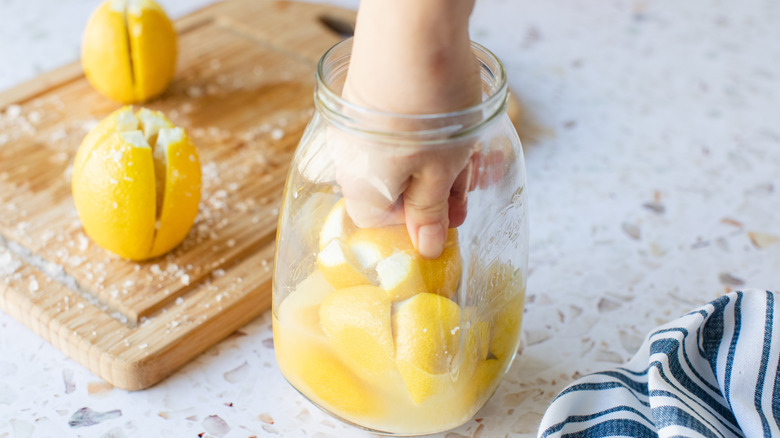 hand pressing lemons in jar