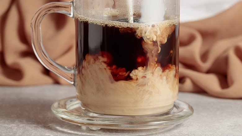 pouring creamer into a cup of coffee