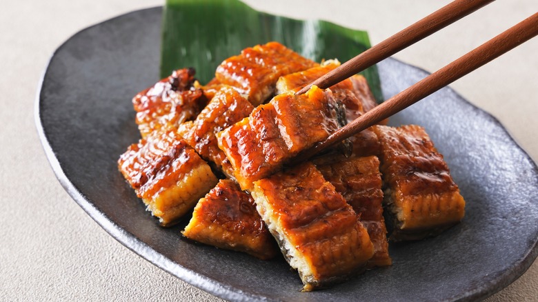 Grilled eel being grabbed with chopsticks